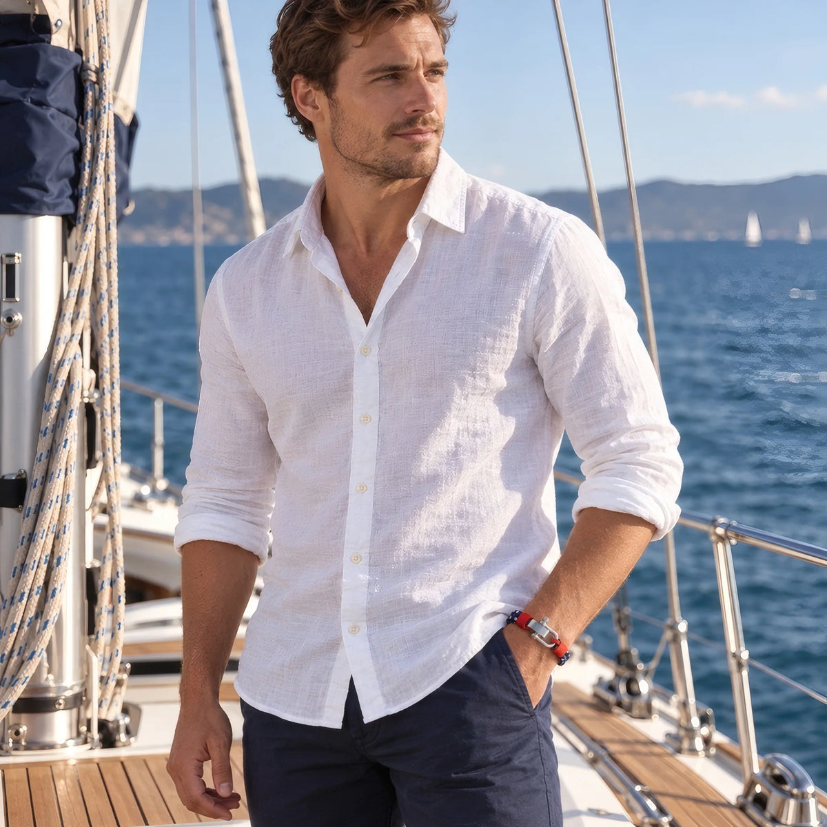 Tenue homme chemise blanche style nautique portant bracelet cordon Nautis sur bateau voilier.