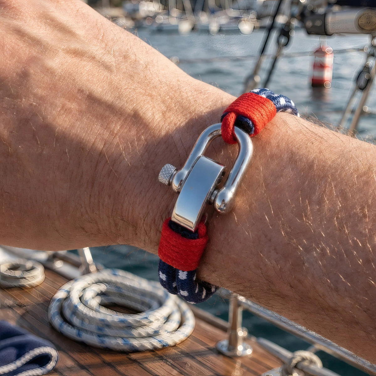 Bracelet Nautis au poignet masculin sur pont bateau manille acier et cordon tricolore marin.