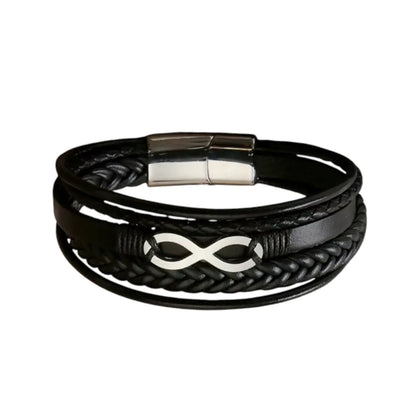 Plan large du bracelet Infini argenté. Le cuir structuré noir multi-rangs met en valeur le fermoir magnétique en acier inoxydable argenté poli sur fond blanc.