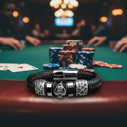 Vue de face, lumière tamisée. Le bracelet Kaldor à plat sur le rebord en bois. Le double motif Pique et Tête de Mort et le maillage du risque sous les projecteurs.