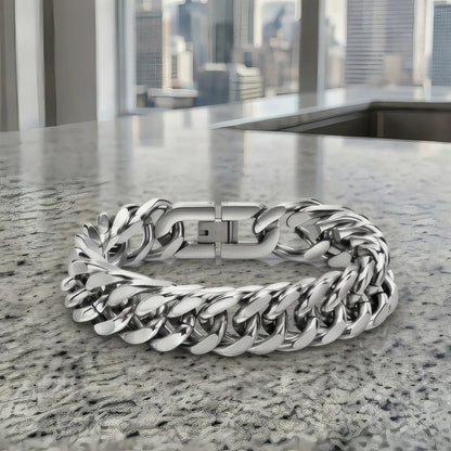 Bracelet maille cubaine poli posé sur granit avec vue sur des gratte-ciels urbains
