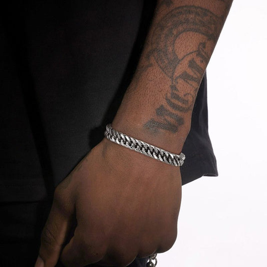 Bracelet cubain sur un poignet d'un homme, ses maillons de douze millimètres et son fermoir sont en acier inoxydable de qualité - coloris brillant argent
