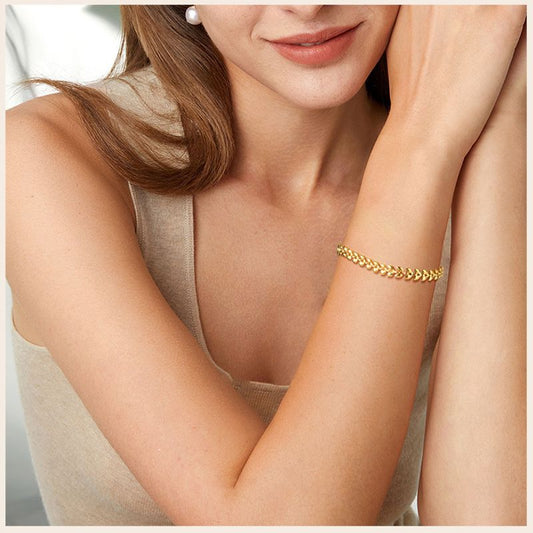 Bracelet à maillons olives dorés en acier inoxydable présenté autour d'un poignet de jolie femme - coloris plaqué or