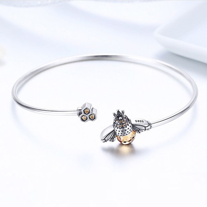Bracelet manchette en argent sterling 925 avec abeille et son abdomen en cristal et son essaim en zircone cubique - bijou présenté sur un poignet de femme vêtu de blanc - coloris argent 
