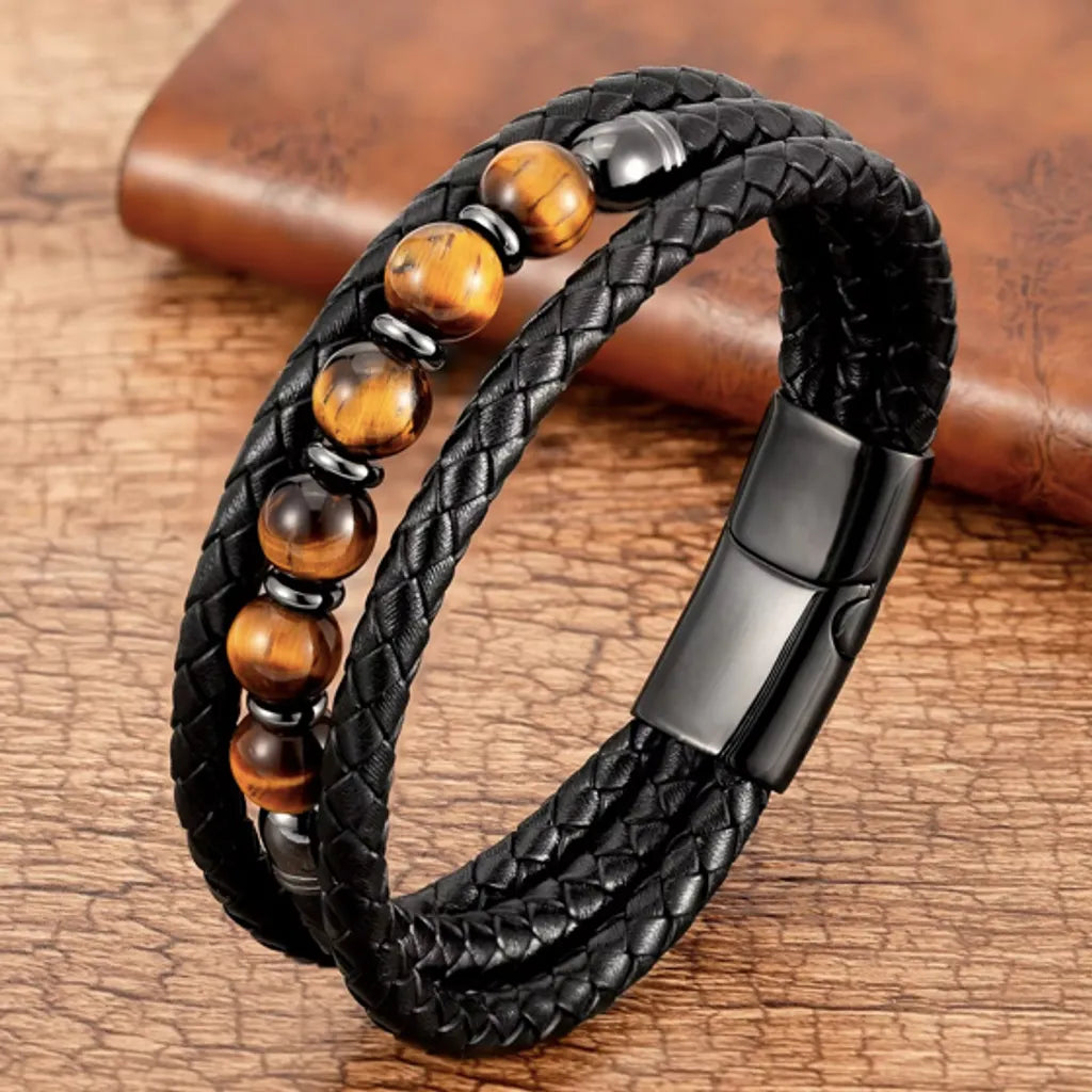 Bracelet en cuir de qualité pour homme avec perles de pierres œil de tigre jaune   posé sur une table rustique.