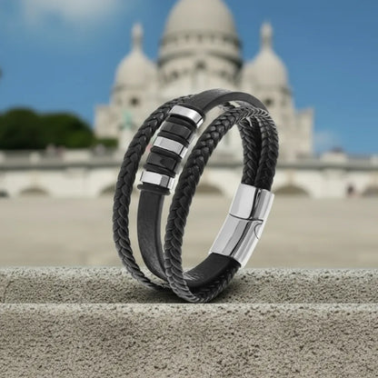 Architecture en mouvement. Le bracelet Nexus cuir noir multi-rangs repose sur la pierre d'une marche devant le Sacré Cœur.