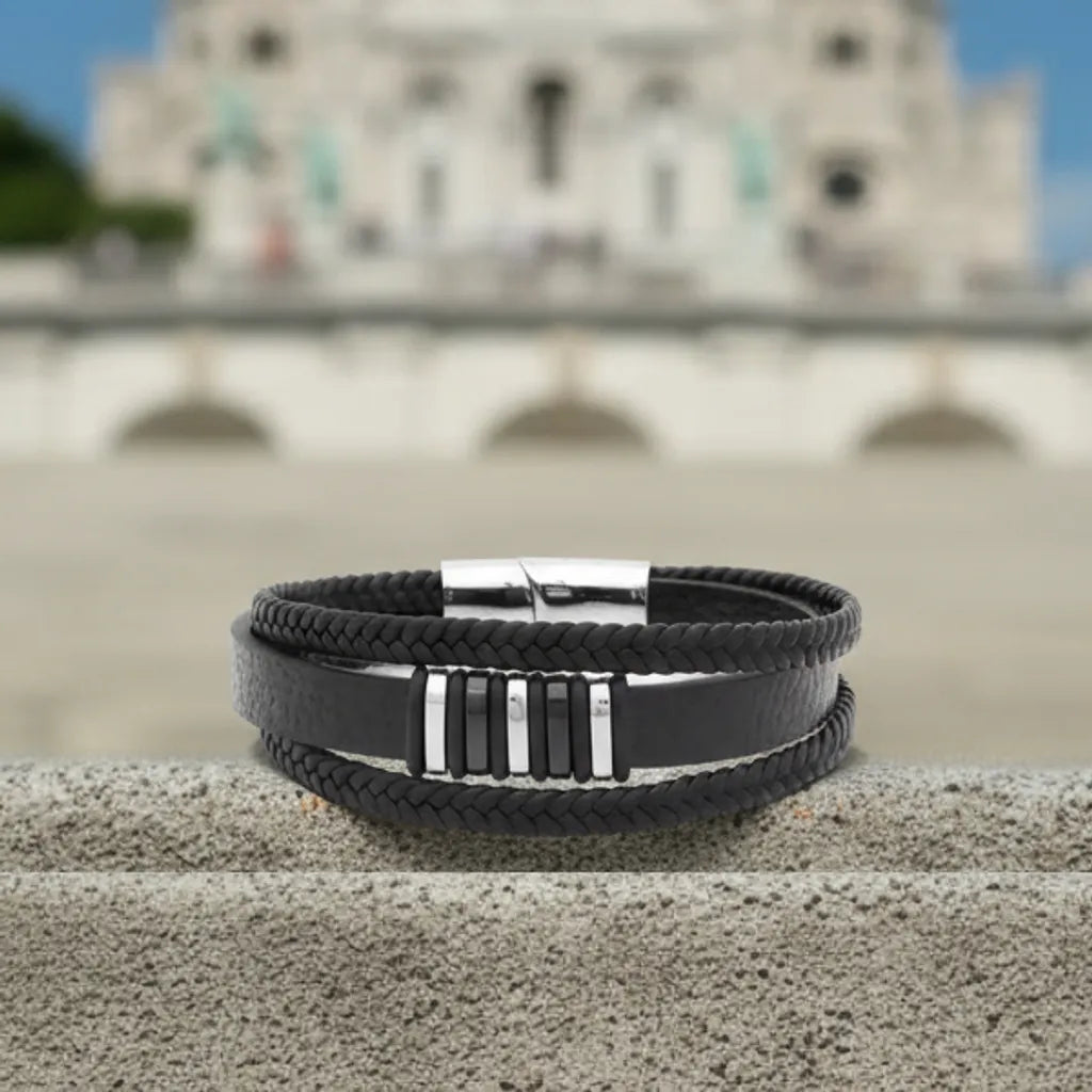 Vue de face. La structure du bracelet Nexus posée à plat, contrastant l'intensité du cuir noir avec la blancheur de la basilique.