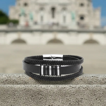 Vue de face. La structure du bracelet Nexus posée à plat, contrastant l'intensité du cuir noir avec la blancheur de la basilique.