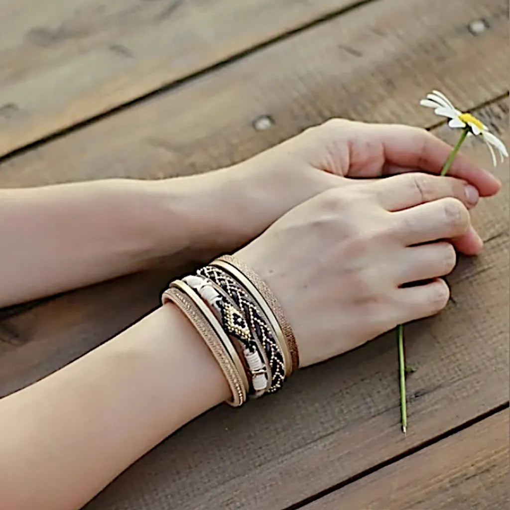 Bracelet Œil du Chaman multi-rangs porté. Son cuir microfibre souple et ses perles fines sont mis en valeur par une marguerite tenue au bout des doigts.