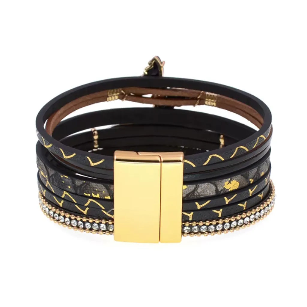 Gros plan sur le fermoir magnétique doré du bracelet papillon lumière noir, dévoilant les différentes couches de cuir microfibre.