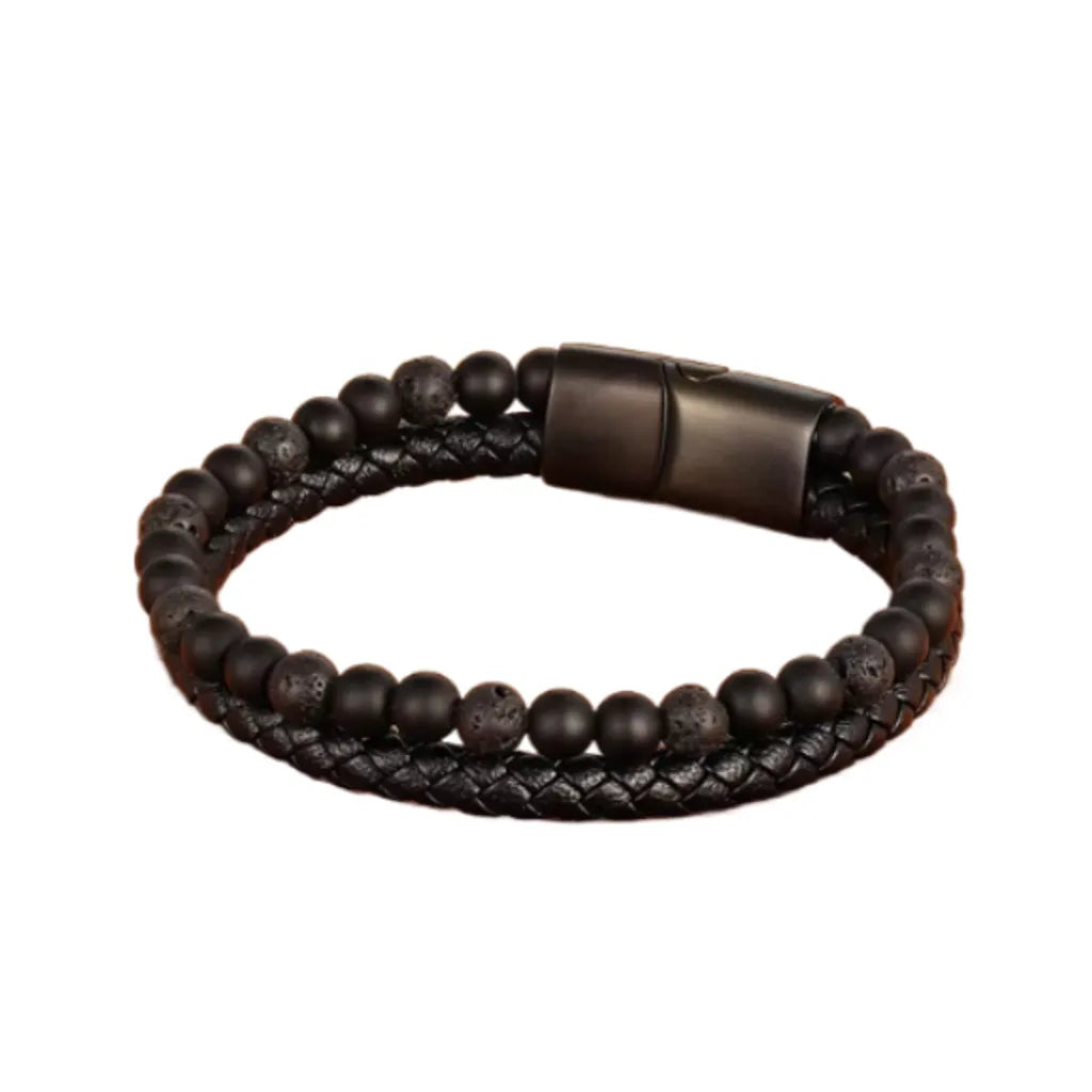 Bracelet en cuir tressé noir décoré de perles de pierre de lave texturée et d’onyx noir, photographié sur un fond blanc pur. Le design minimaliste met en valeur la qualité artisanale et le style moderne de cet accessoire unique.