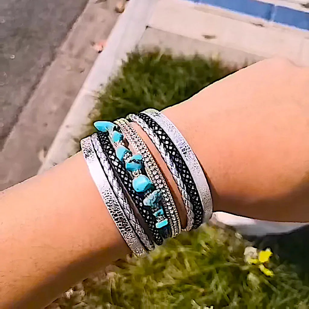 Gros plan du bracelet Pierre Horizon porté au poignet d'une femme, avec un décor de verdure et de trottoir urbain.