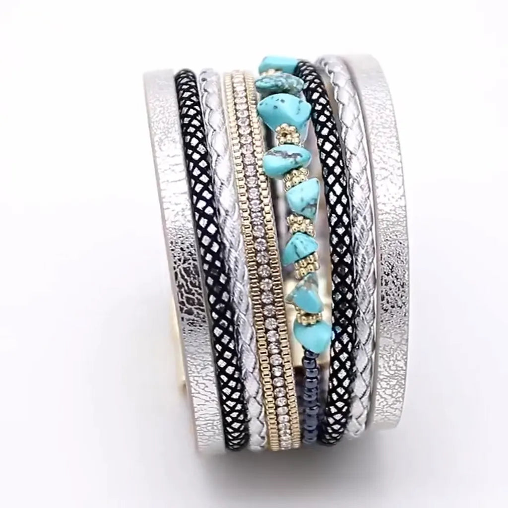 Vue de profil d'un bracelet Pierre Horizon dressé sur son fermoir, détails du multi-rangs, cuir microfibre argenté et pierres turquoise.