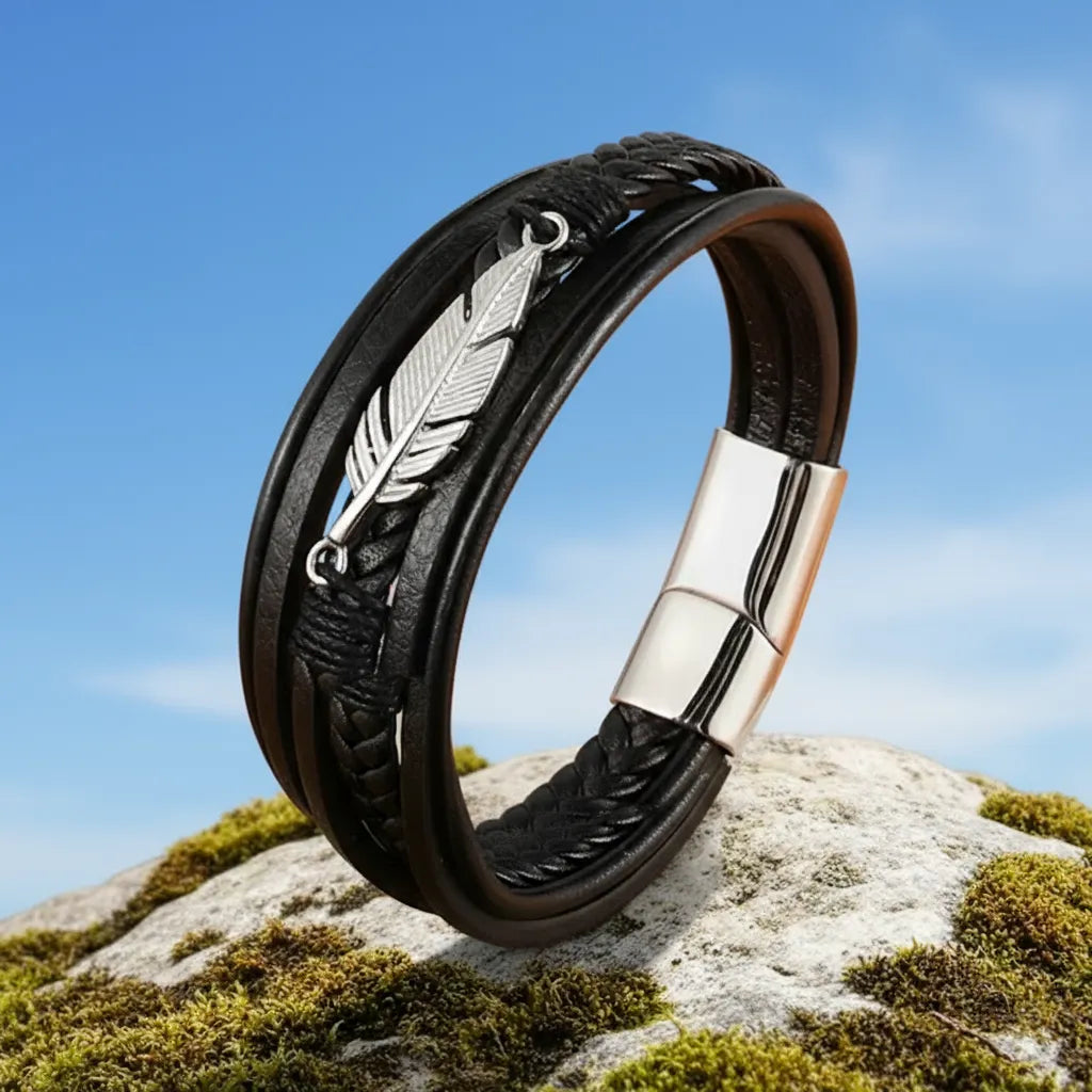 Vue 3/4 de profil du bracelet en cuir Plume Liberté, multi-rangs, dressés sur un rocher. On voit le fermoir magnétique sur fond de ciel.