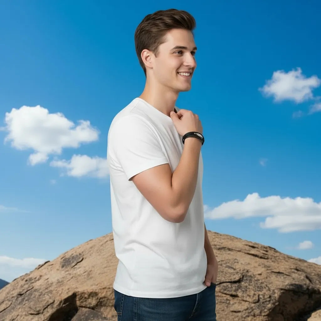Vue de profil d'un homme en t-shirt blanc. Il met en évidence le bracelet multi-rangs Plume Liberté en cuir noir et plume argentée sous un ciel bleu légèrement nuageux.