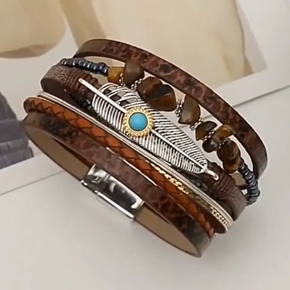Gros plan rapproché sur les rangs du bracelet marron, révélant la texture du motif peau de serpent et un rang de perles noires, ainsi que la breloque plume.