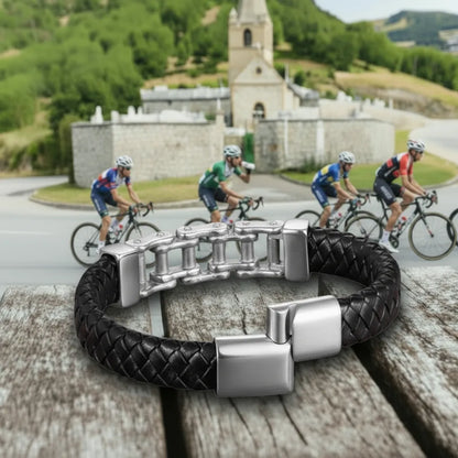 Détail de sécurité. Le bracelet Pulsar cuir tressé noir, fermoir entrouvert, mettant en valeur la chaîne de vélo en acier. L'élégance du cuir tressé sur fond de montagne.