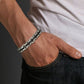 Bracelet Steel porté sur un poignet d'homme ayant sa main dans la poche de son jean noir - bracelet à maillons en acier inoxydable - bijou raffiné masculin