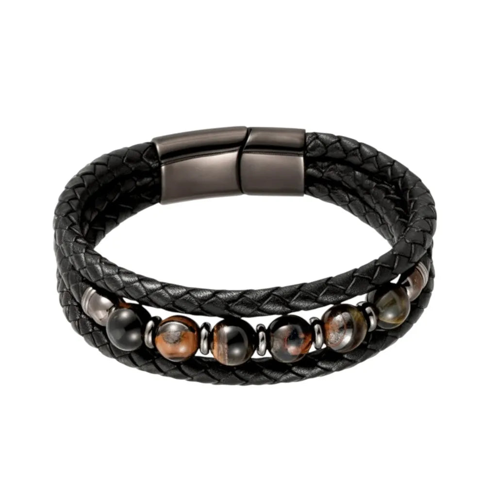 Détail du bracelet Talis aux multi-rangs tressés. Le motif principal est composé de perles œil de tigre bleues aux nuances brunes sur la lanière centrale de cuir noir souple et texturé.