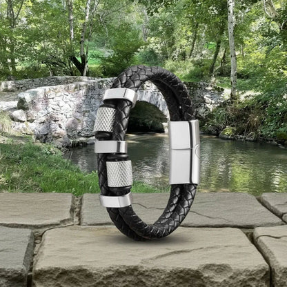 Ambiance automnale. Le bracelet Talon en cuir tressé dressé sur la murette de pierre. Les cylindres moletés en acier reflètent la lumière de la rivière du Tarn. Précision en pleine nature.
