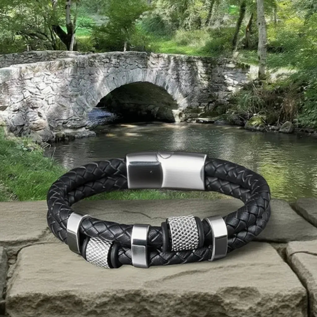 Vue d'architecture. Le bracelet Talon cuir tressé noir posé, son moletage contrastant avec la pierre ancienne du pont de Nages. Un accessoire de grip et de caractère.