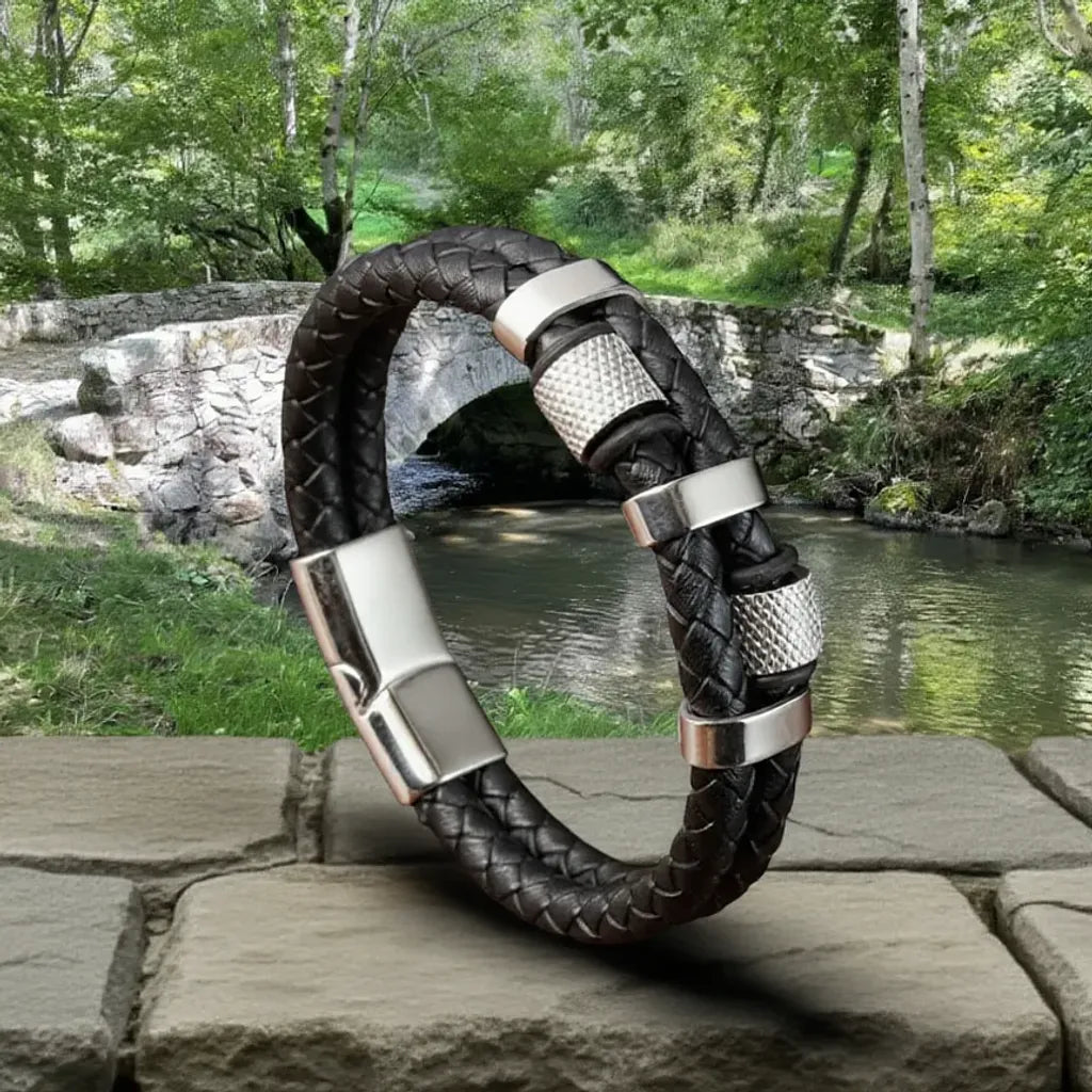 Composition équilibrée. Le bracelet Talon en équilibre, soulignant la force du double cuir tressé. Les cylindres moletés et les bagues ovales rappellent les mécanismes du pont.