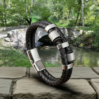 Composition équilibrée. Le bracelet Talon en équilibre, soulignant la force du double cuir tressé. Les cylindres moletés et les bagues ovales rappellent les mécanismes du pont.