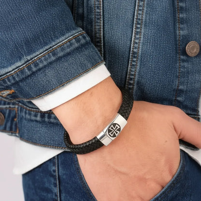 Gros plan du bracelet Croix Pattée porté au poignet d'un homme en jean, main dans la poche.