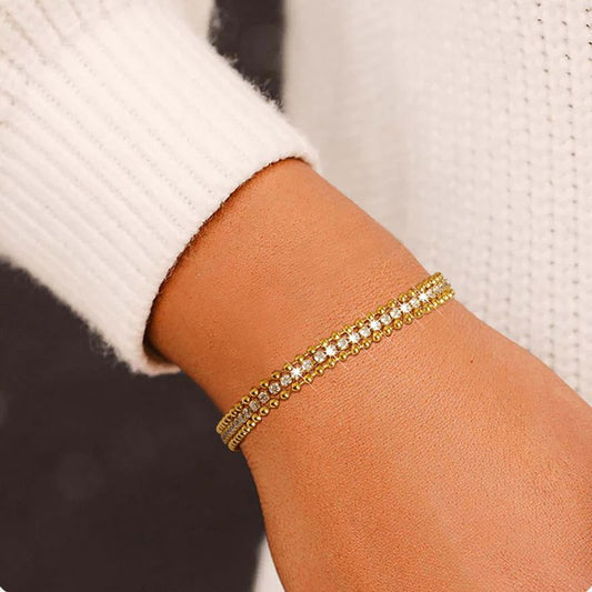 Bracelet tennis chaîne à bille en acier inoxydable plaqué or avec rivière zircone cubique - bracelet chaîne présenté sur un poignet de femme avec un pull blanc