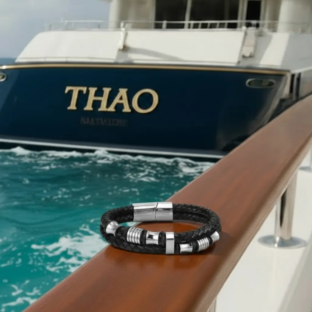 Vue intégrale. Posé à plat sur le bois nautique, le bracelet Thao cuir tressé aligne ses perles diabolo en harmonie avec le décor du yacht.