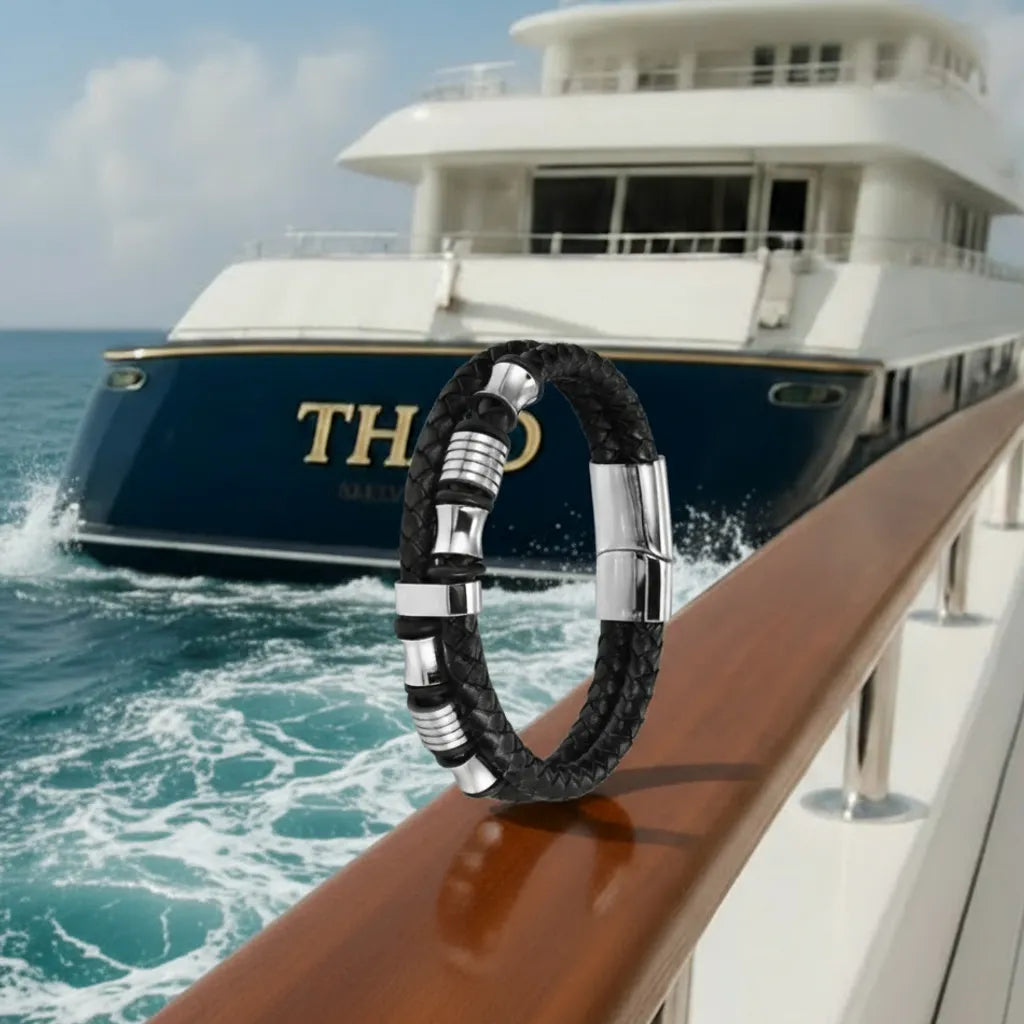 Le bracelet Thao repose en équilibre sur la rampe en acajou. La double lanière en cuir noir tressé contraste avec l'éclat des perles diabolo sur fond du quai nautique.