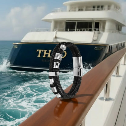 Le bracelet Thao repose en équilibre sur la rampe en acajou. La double lanière en cuir noir tressé contraste avec l'éclat des perles diabolo sur fond du quai nautique.