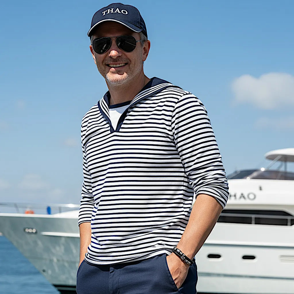 Vue portée. Le bracelet Thao s'intègre au style marinière. La largeur du cuir noir tressé et le fermoir soulignent l'équilibre des formes.