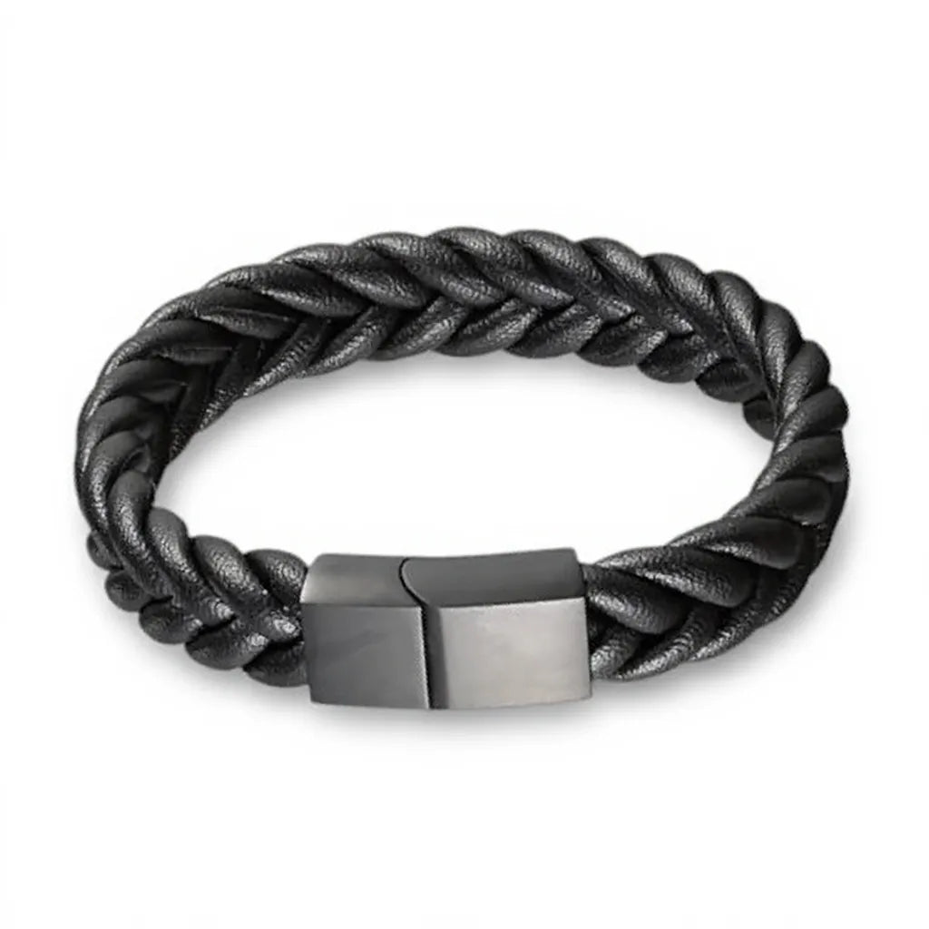 Gros plan texture. Le bracelet Torc révèle son tressage rond à 4 lanières et sa densité. La finition du fermoir en acier inoxydable noir renforce la présence du cuir souple noir.