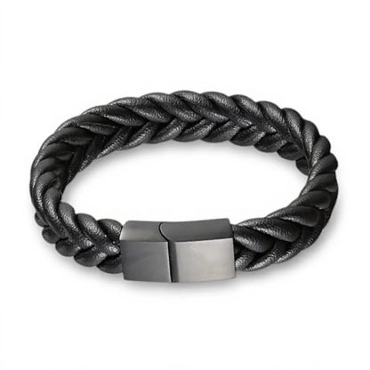 Gros plan texture. Le bracelet Torc révèle son tressage rond à 4 lanières et sa densité. La finition du fermoir en acier inoxydable noir renforce la présence du cuir souple noir.