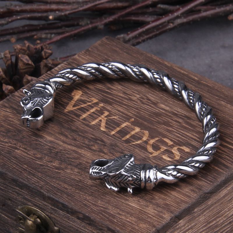 Bracelet torque viking avec têtes d'ours nordique en acier inoxydable - jonc ouvert posé sur sa boite cadeau en bois foncé signé Vikings - Manchette torsadée coloris argent