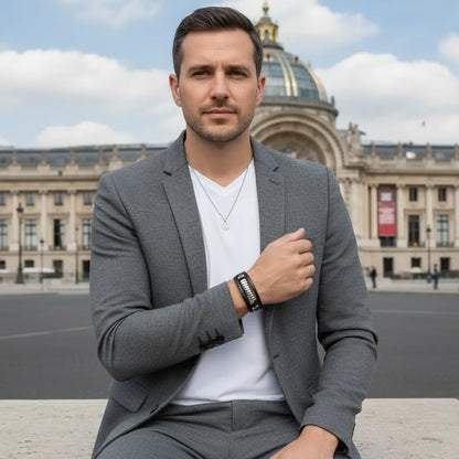 Plan poitrine. L'homme pensif, la main au cœur, arborant le bracelet Torus cuir texturé noir multi-rangs. L'élégance du ressort acier au poignet.