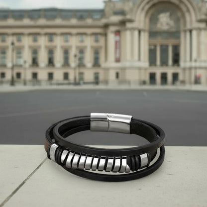 Focus sur le dynamisme. Gros plan sur le ressort acier central du bracelet Torus, contrastant avec le cuir texturé noir et le granit.