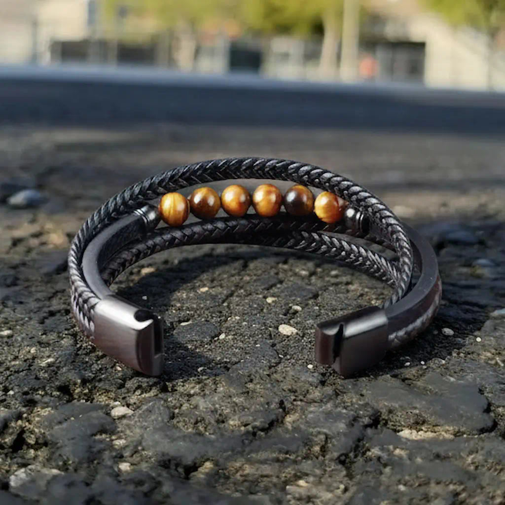 Détail du fermoir magnétique en acier brossé ouvert, dévoilant la mécanique du modèle Vorg. Le bracelet expose la souplesse de son cuir noir et le montage sécurisé des ornements oeil de tigre face à l'immensité du stade.