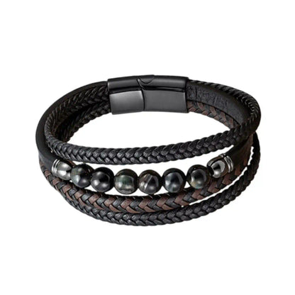 Focus sur les nuances froides des perles oeil de tigre bleu scandinave intégrées au tressage complexe du bracelet Vorg. L'alliance du cuir texturé et des reflets azurés crée une esthétique technique et souveraine.