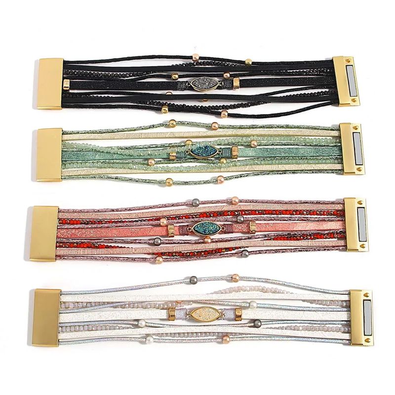 Bracelets Pierre Bohème – wrap pour femme avec perles, lanières en cuir PU et breloque doré avec pierre de résine ovale, ces multilanière sont présentés à plat et ouvert sur un plan de travail blanc. Quatre coloris disponibles, noir, vert, rose et blanc.