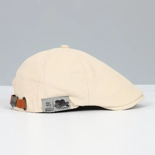Casquette plate beige pour homme, vue de profil, avec sangle ajustable et étiquette latérale en tissu, combinant confort et élégance dans un style rétro moderne.