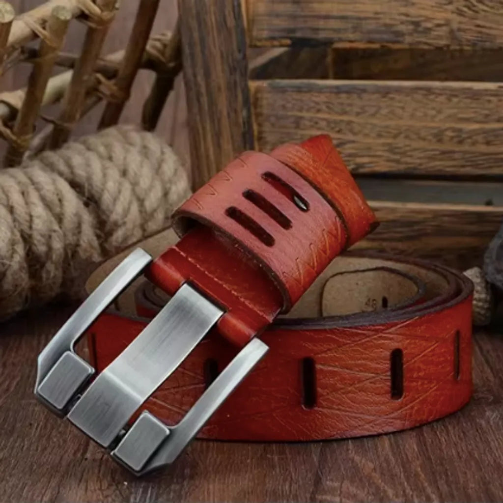 Ceinture pour homme en cuir de vache enroulée autour d'elle-même avec revêtement de protection texturé, anti-rayure. On découvre son large passant ajouré par trois fentes, juste au-dessus de sa majestueuse boucle ardillon en métal robuste argenté – coloris de la lanière, cognac orangé. La décoration rustique est typiquement en bois.