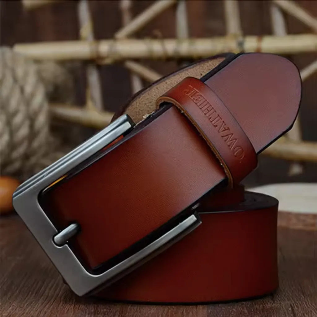 Ceinture pour homme en cuir véritable lisse, lanière en cuir de vache avec revêtement de protection. Sa boucle ardillon en métal est argentée et rectangulaire. Passant avec marque COWATHER gravé. Présentation fermée et enroulée sur les lames d'un parquet en bois. Coloris cognac.