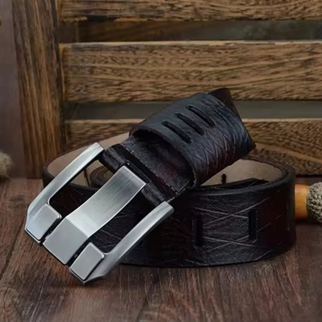 Ceinture pour homme en cuir de vache enroulée autour d'elle-même sur un beau parquet en bois. Cette bande de cuir supporte un revêtement de protection texturé, anti-rayure. On découvre son large passant ajouré par trois fentes, juste au-dessus de sa majestueuse boucle ardillon en métal robuste argenté – coloris de la lanière, café. Décoration typiquement en bois et rustique.