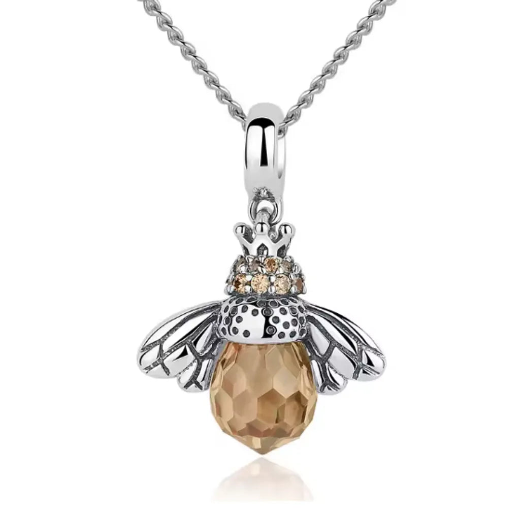 Gros plan sur un pendentif en forme d’abeille royale en argent 925, finition rhodiée avec cristal jaune miel, chaîne fine assortie, design raffiné et féminin.