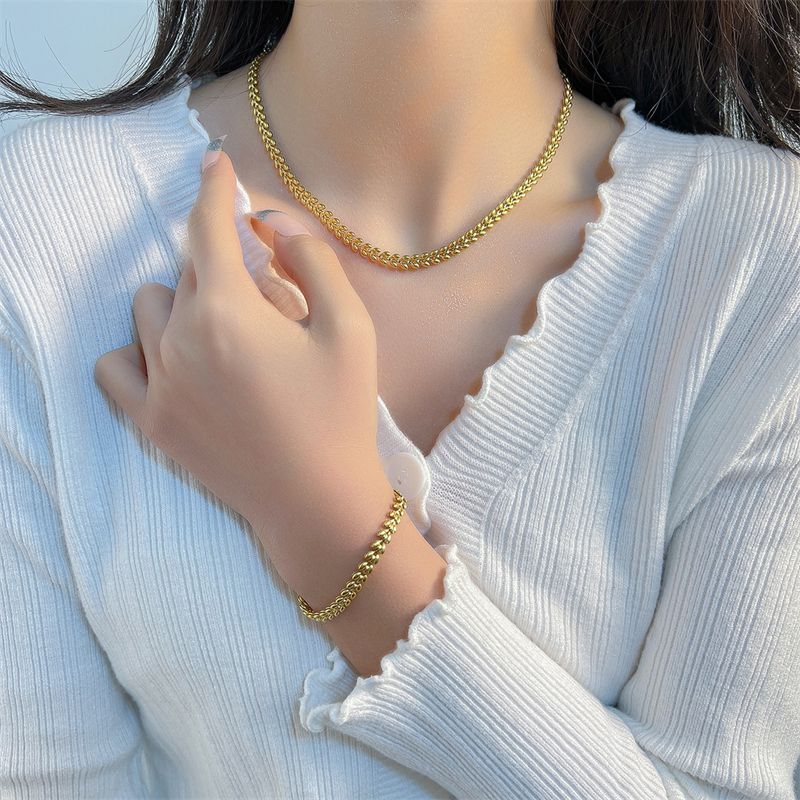 Collier chaîne et bracelet à maillons olives plaqués dorés en acier inoxydable autour du cou et du poignet d'une belle femme brune - coloris or - coloris plaqué or