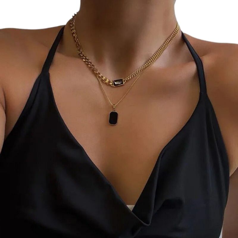 Collier géométrique avec pendentif octogone rectangle en émail noir et acier inoxydable suspendu au bout d'une chaine vénitienne autour du cou d'une femme vêtue de noir - coloris or