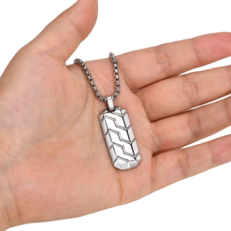 Vu sur la paume d'une main d'homme du collier pendentif profil de pneu en acier inoxydable - chaine vénitienne et pendentif géométrique de couleur argent