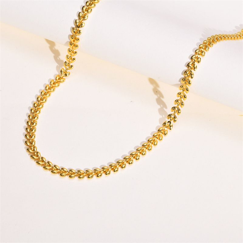 Collier chaîne à maillons olives dorés en acier inoxydable pour femme posé à plat sur un support blanc - coloris plaqué or